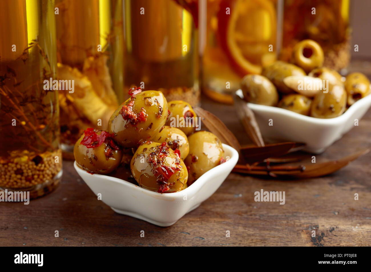 Aceitunas verdes condimentadas y botellas con aceite de oliva sobre una  mesa de madera Fotografía de stock - Alamy