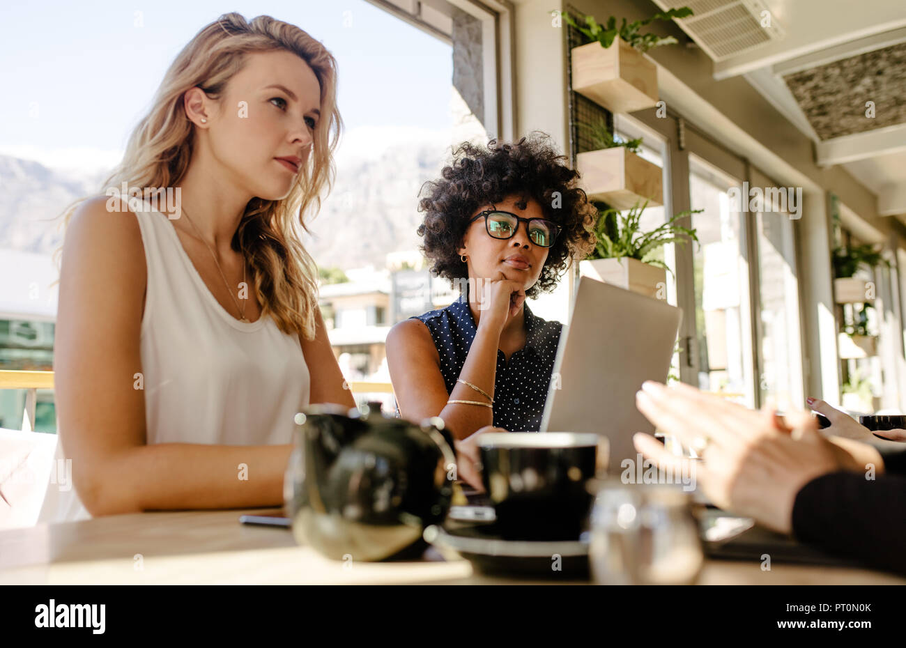 Mujer sentada en el café y discutir nuevas oportunidades de negocio.  Reunión de empresarias multiétnica en la cafetería para la discusión del  proyecto Fotografía de stock - Alamy