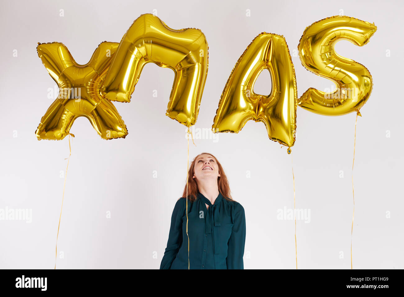 Mujer joven con globos de oro la construcción de la palabra 'xmas' Foto de stock