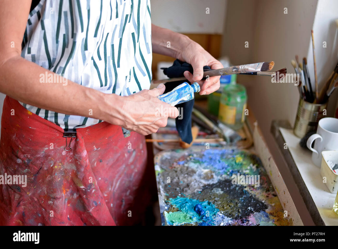 Pintor femenino en su atelier, tubo de pintura y pinceles Foto de stock