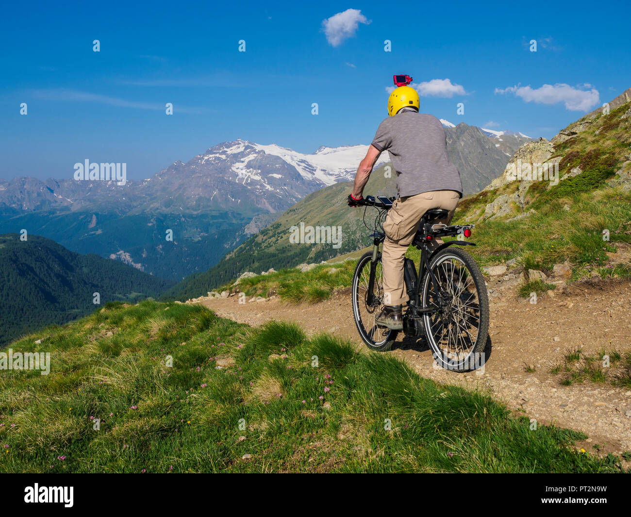 Italia Lombardía, Passo di Val Viola, hombre caballo e-bike en las montañas con acción cam en su casco Foto de stock