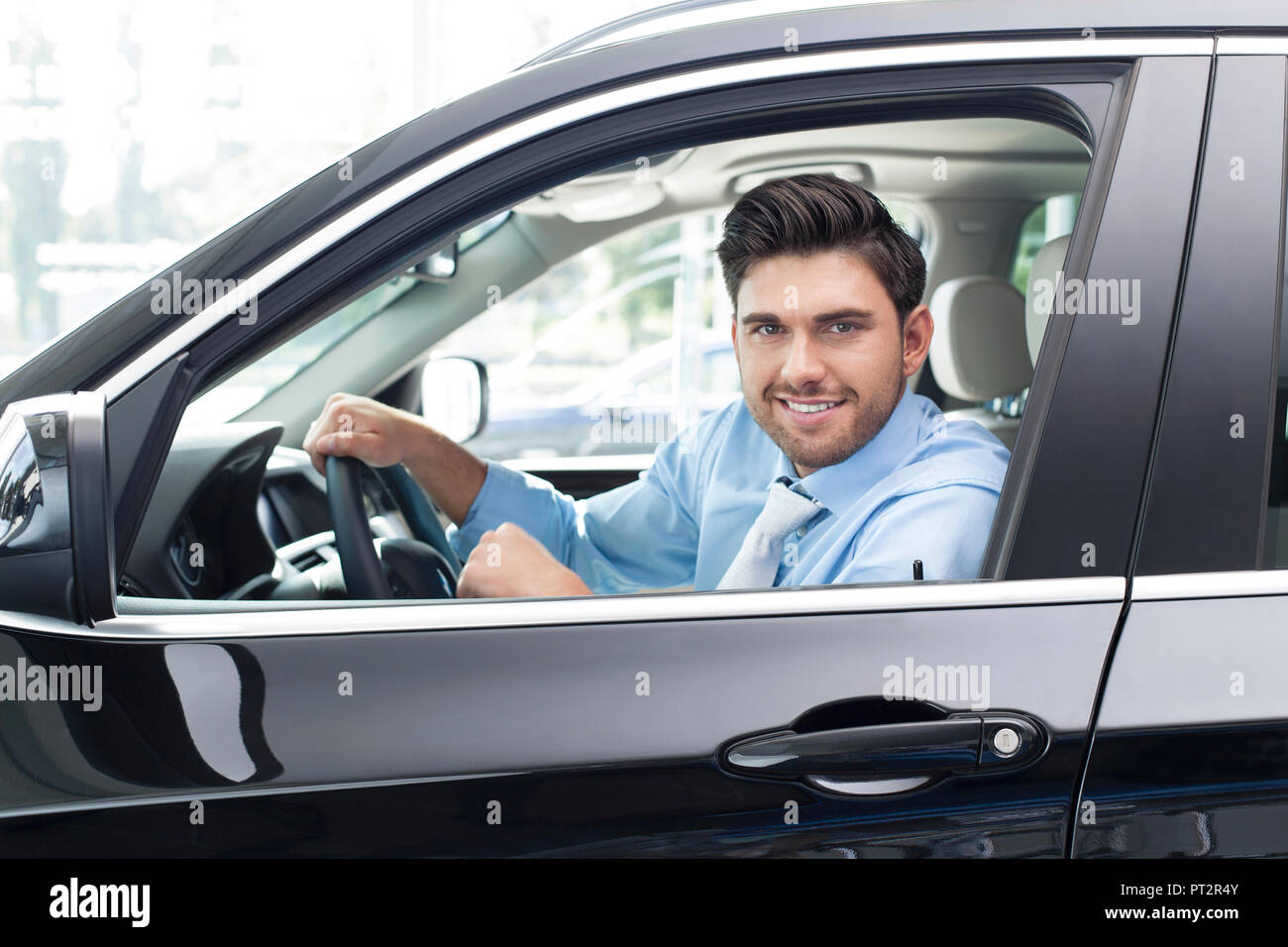 En el concesionario de coches, el hombre sentado en el coche nuevo Foto de stock