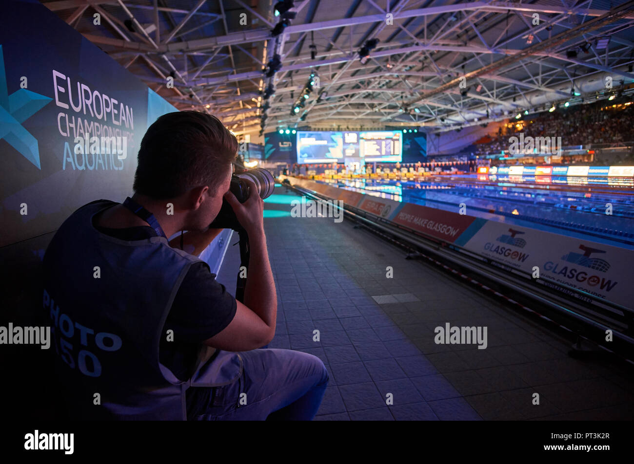 Fotógrafo de prensa trabaja sobre la cesión durante un evento de natación en Glasgow en los Campeonatos Europeos de 2018. Foto de stock