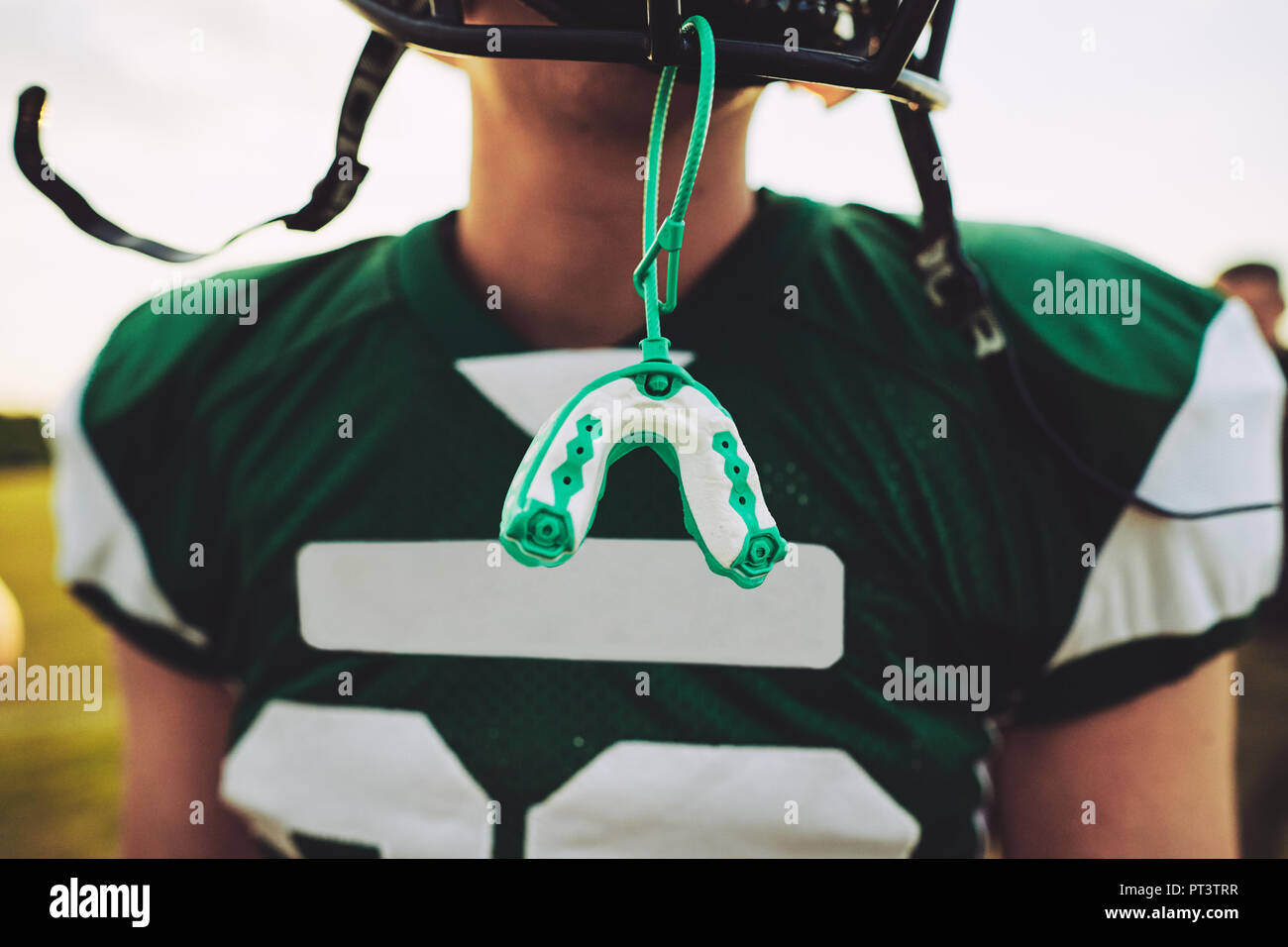 Primer plano de un protector bucal colgando el casco de un jugador de fútbol americano durante una sesión de práctica en equipo Foto de stock