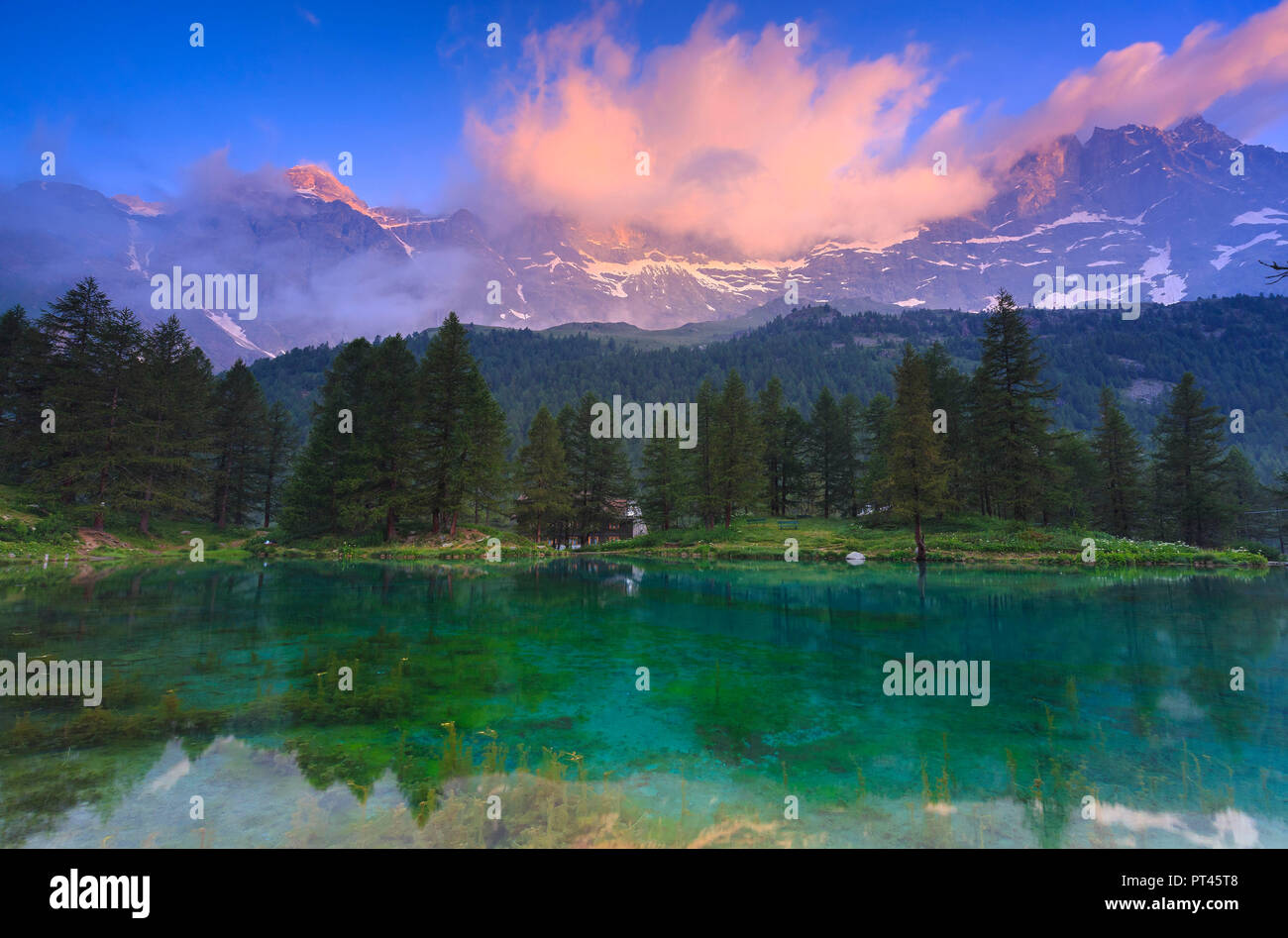 Nube iluminada por los colores del amanecer se refleja en el lago Azul, Azul Lago, Cervinia, Valtournanche, Valle de Aosta, Italia, Europa Foto de stock