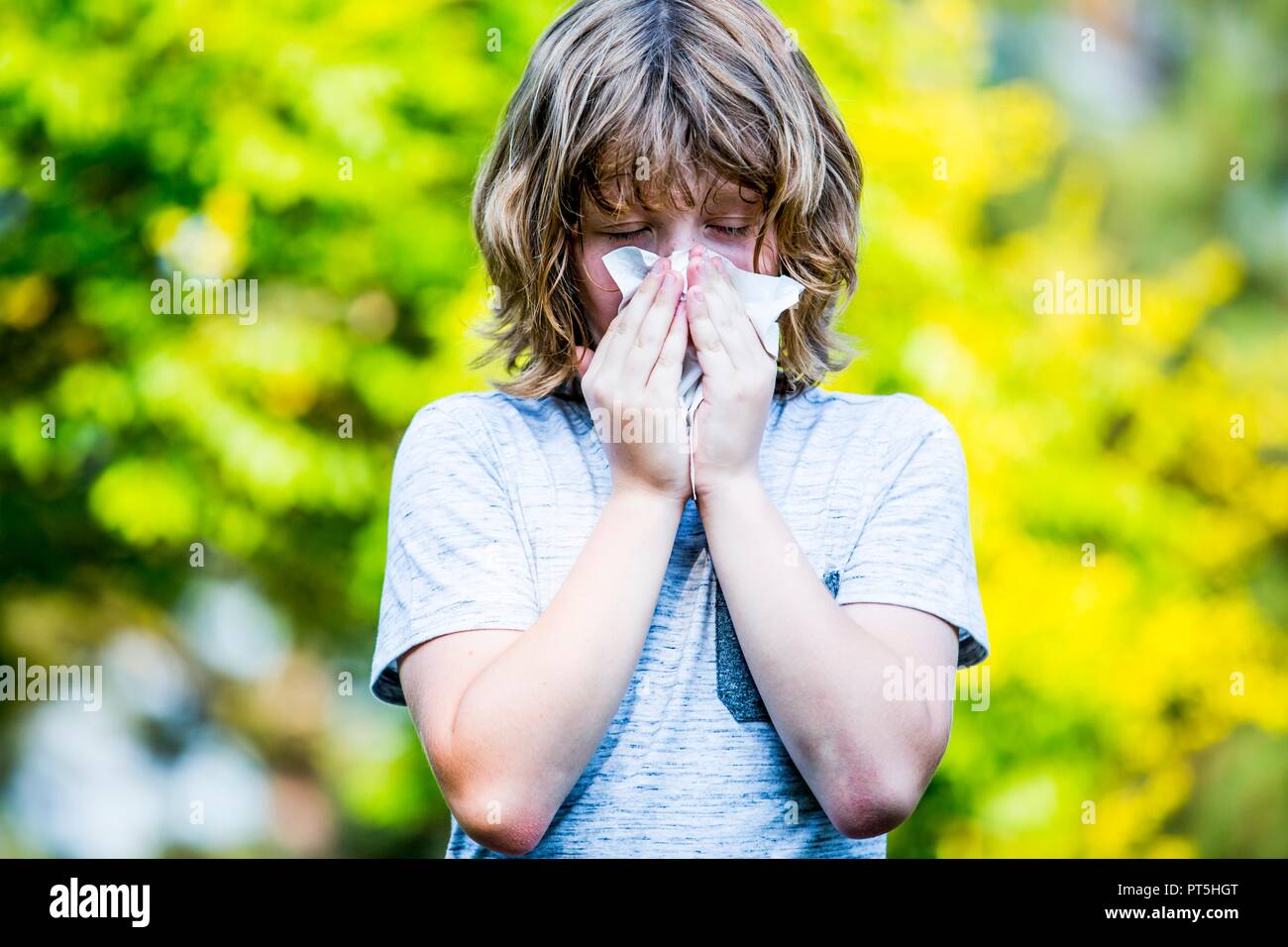 Niño con pañuelo al estornudar. Foto de stock