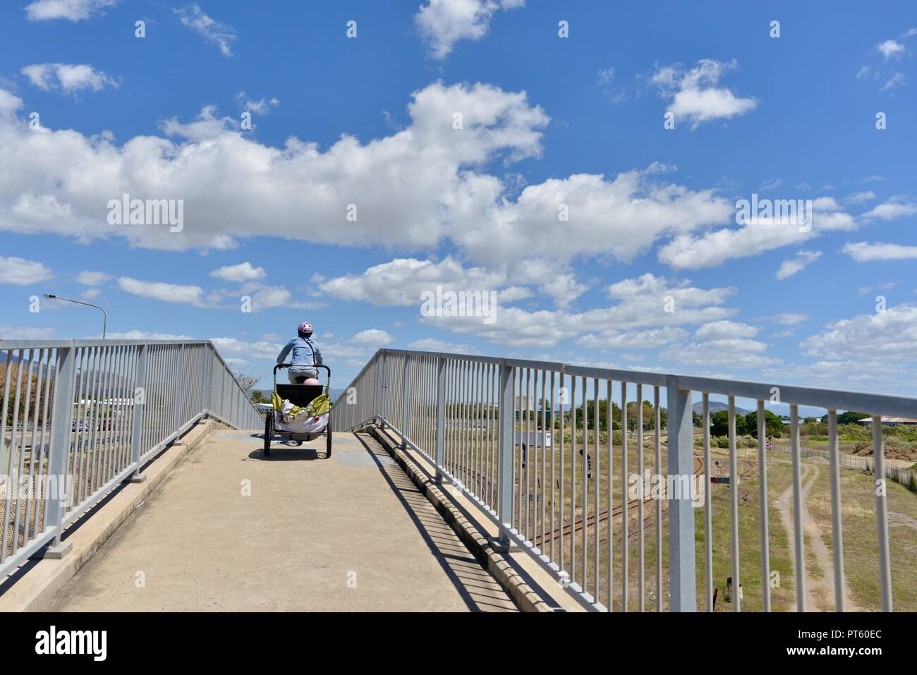 Mujer en bicicleta con un remolque de bicicleta para niños, Townsville, Queensland, Australia Foto de stock