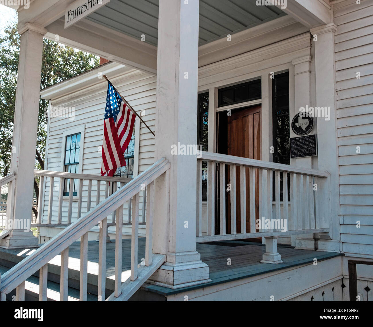 Entrada frontal de blanco shingled casa con pasos. Casa más antigua en pie en Mckinney, Texas, plaza de castaños. Build 1854. Bandera Americana en polo extendido Foto de stock