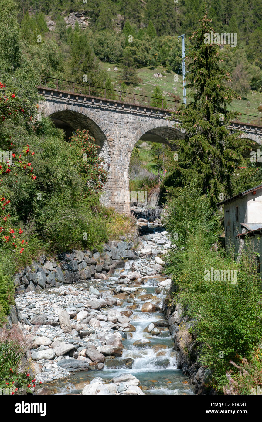 Arcos de piedra del puente del tren sobre un arroyo en Lavin es un municipio en el distrito de Inn, en el cantón suizo de los Grisones Foto de stock