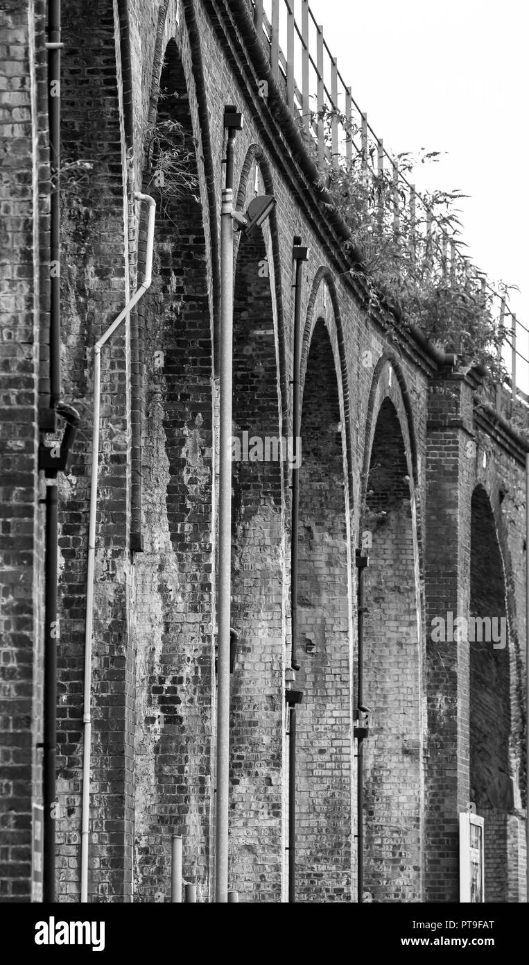 Vista en blanco y negro de los arcos del viaducto del ferrocarril victoriano, Worcester City Center, Reino Unido. Vista de gusano de la arquitectura exterior. Foto de stock