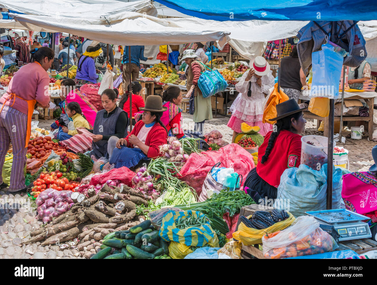 Las mujeres peruanas en coloridos trajes tradicionales y sombreros vender frutas y verduras en el mercado dominical en Pisac, Perú, América del Sur. Foto de stock