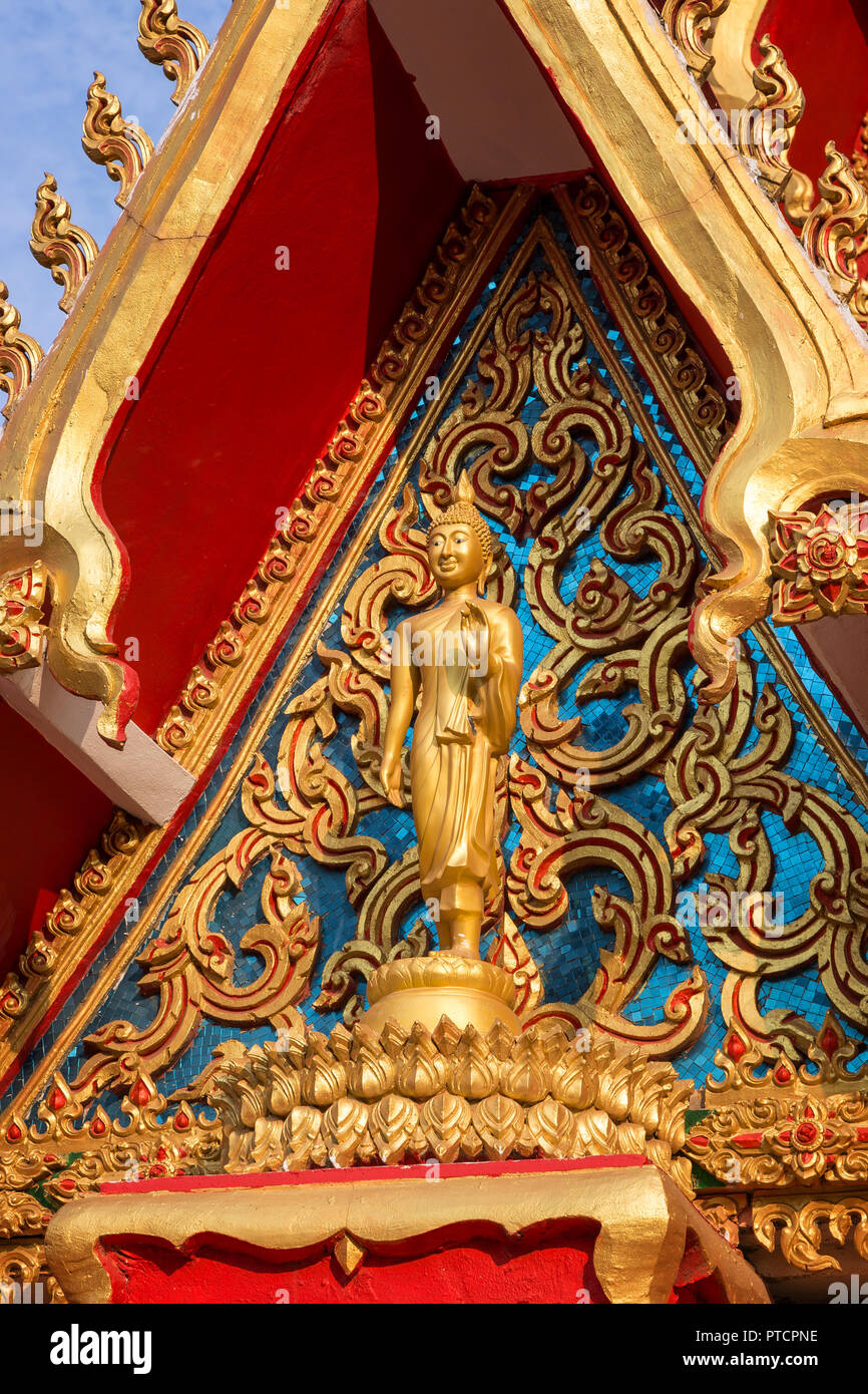 Cerca de una estatua de Buda y ornamentada fachada e intrincado del budista Wat Chanthaburi (Chanthaboury) templo en Vientiane, Laos, en un día soleado. Foto de stock