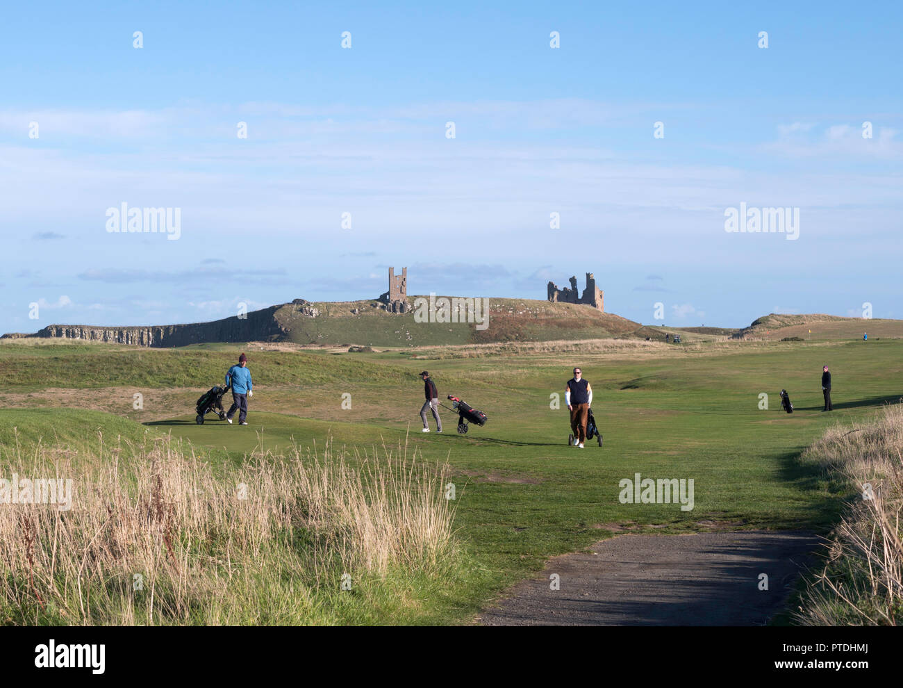 Los golfistas en el castillo de Dunstanburgh wheeling carritos de Golf, Northumberland, Inglaterra, Reino Unido. Foto de stock