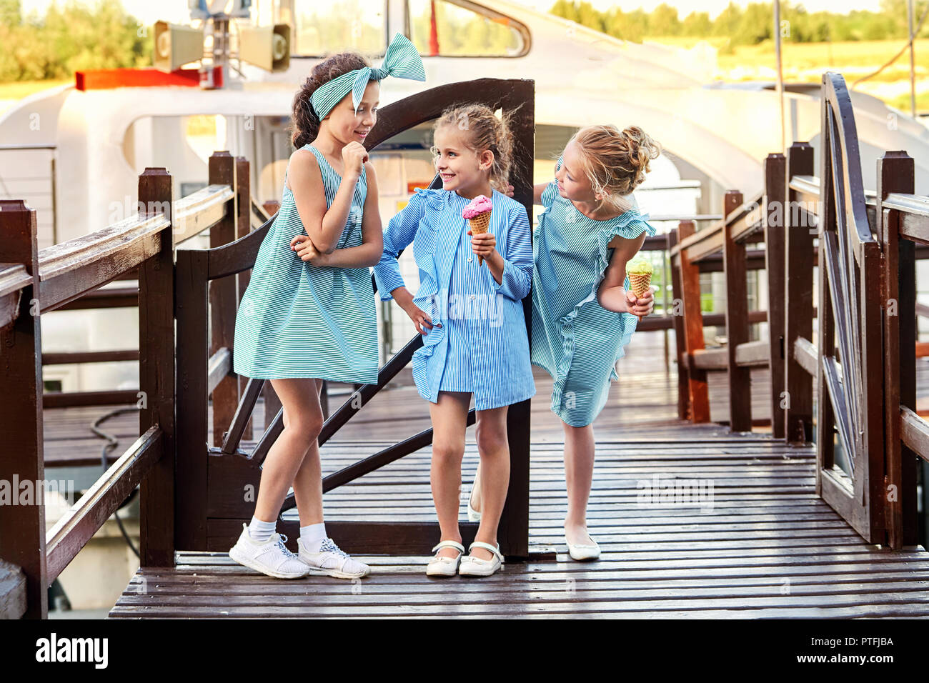 Grupo 3 dama moda niños vestidos a rayas elegante en estilo cool,ropa de verano al aire libre.Designer children's collection.La juntos,parado en el puente de stock - Alamy