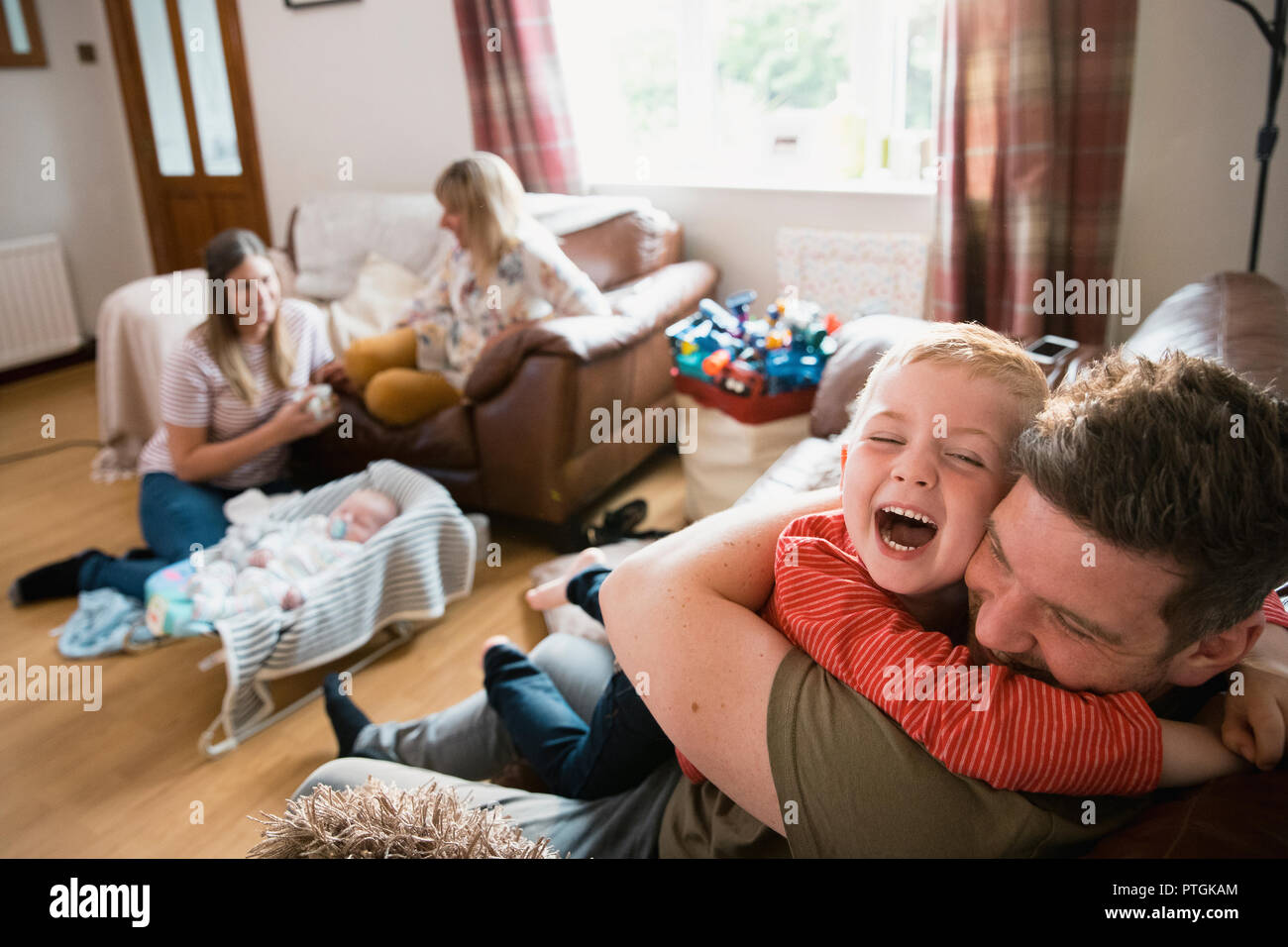 Familia con dos niños y su abuela sentada en el salón con sofás. Son relajantes, mirar televisión y conversar. La abuela ha. Foto de stock