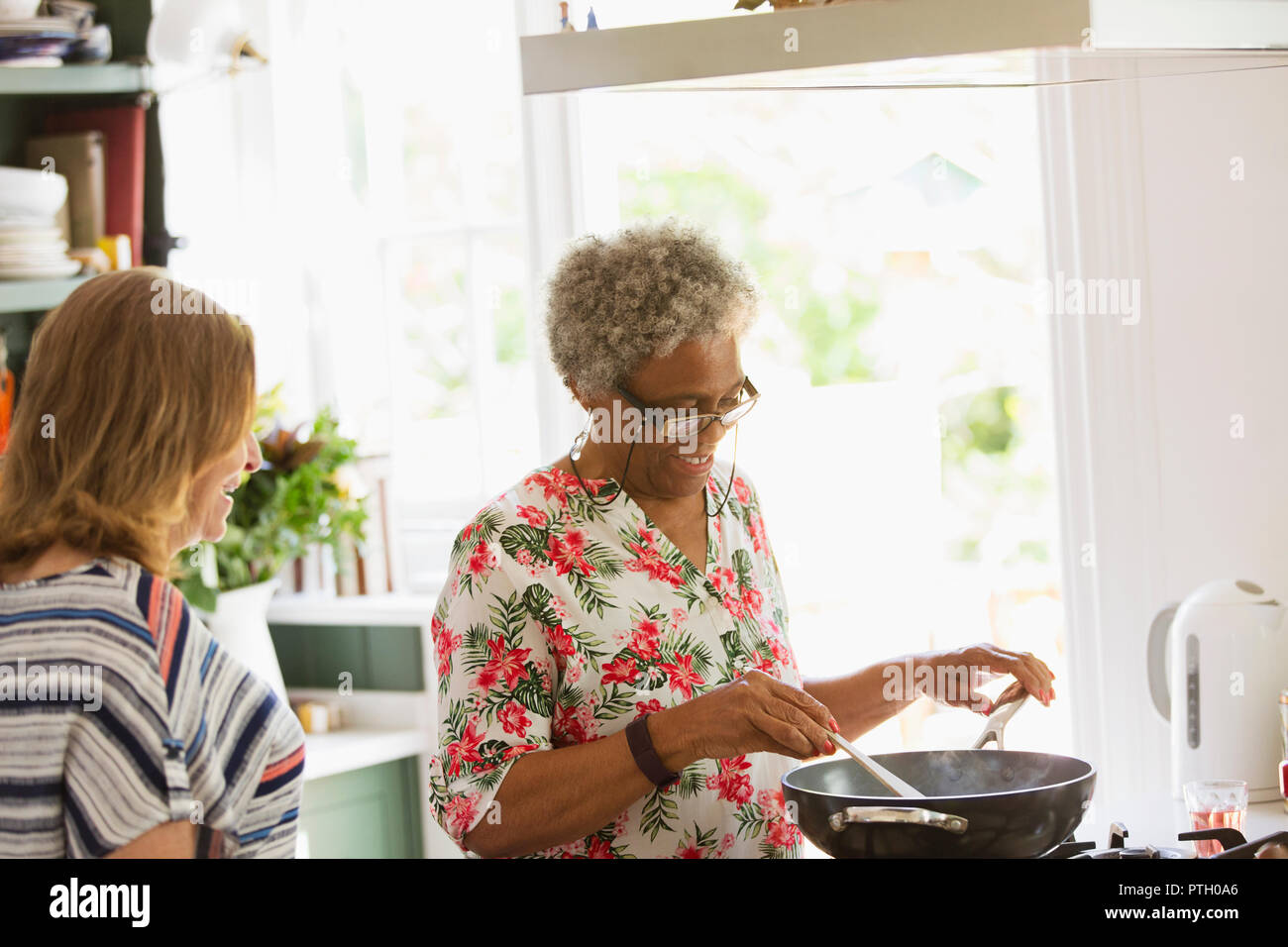 Las mujeres mayores a la estufa de cocina en la cocina Foto de stock