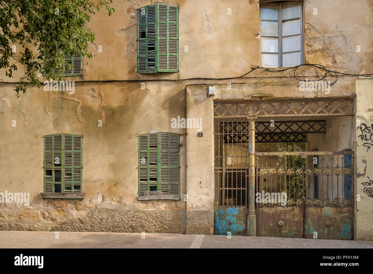 Tiempo gastado oxidada, persianas y puertas de hierro forjado en la fachada de un edificio en el casco antiguo de la ciudad, Alcudia, Mallorca, España Foto de stock