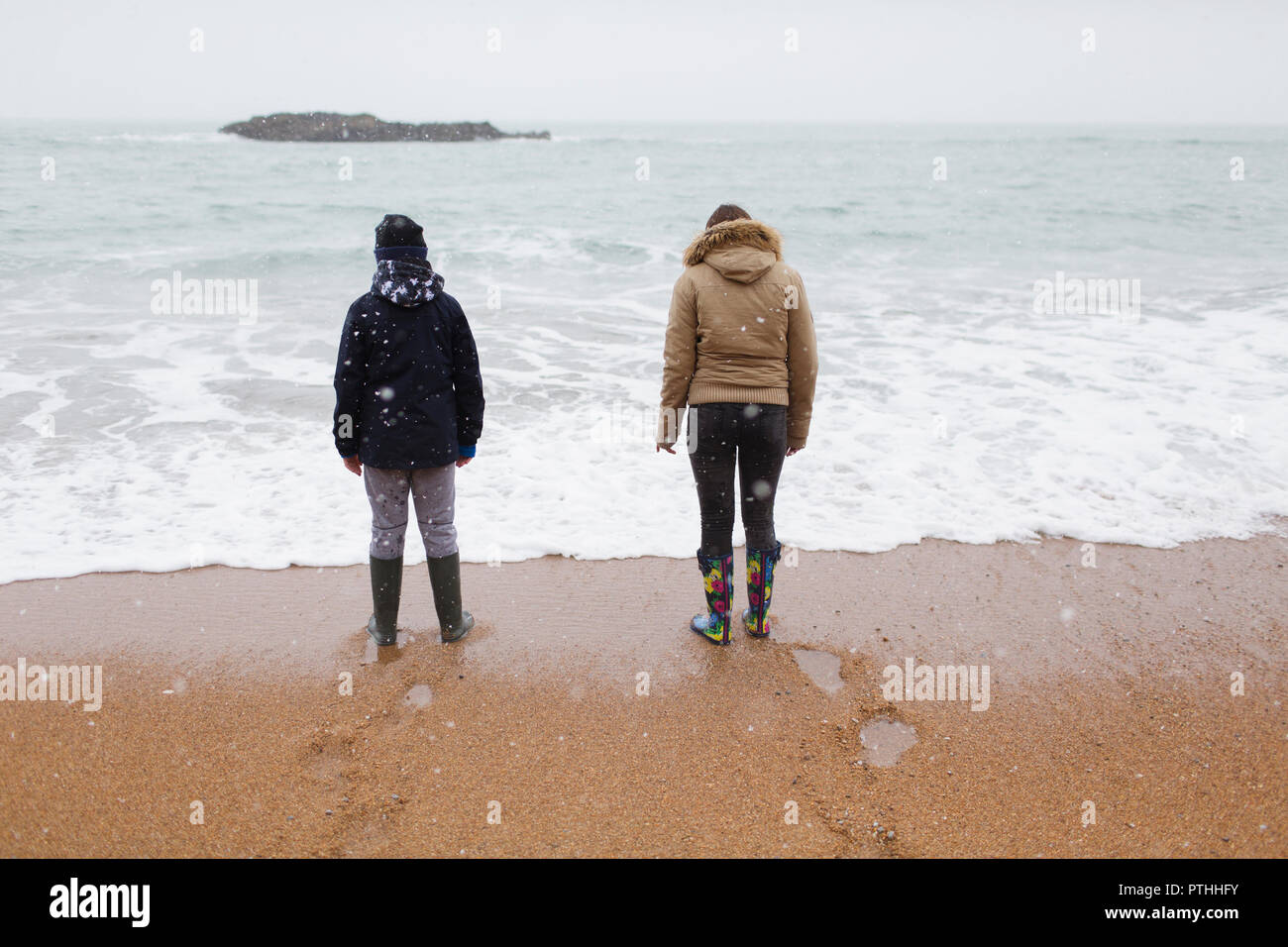 Hermano y hermana en ropa de abrigo en invierno con nieve playa permanente Foto de stock