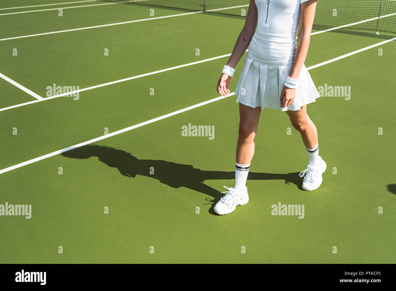 Captura recortada del jugador de tenis femenino en blanco sportswear caminar sobre la pista de tenis Foto de stock