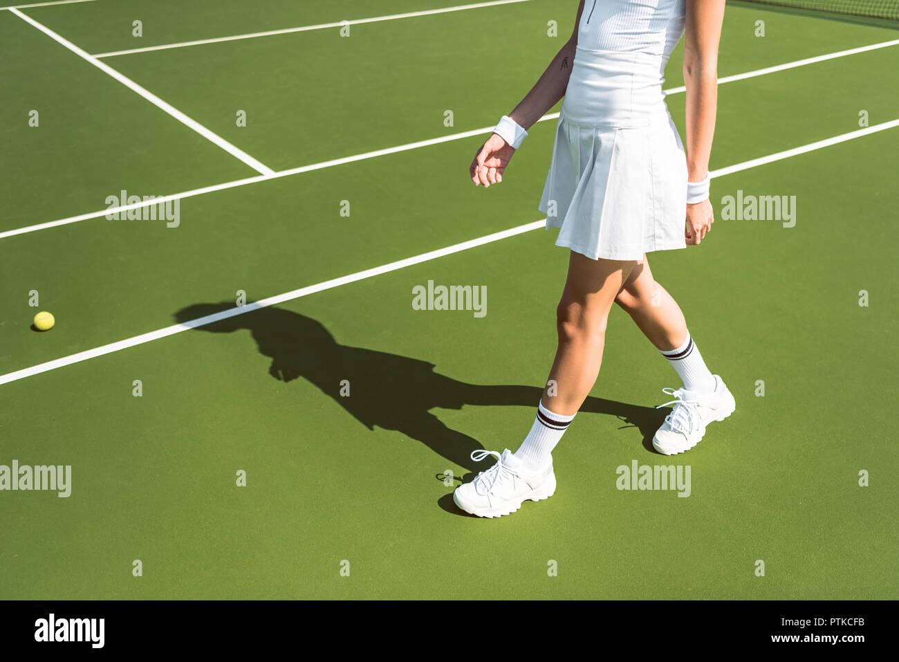 Captura recortada del jugador de tenis femenino en blanco sportswear caminar sobre la pista de tenis Foto de stock
