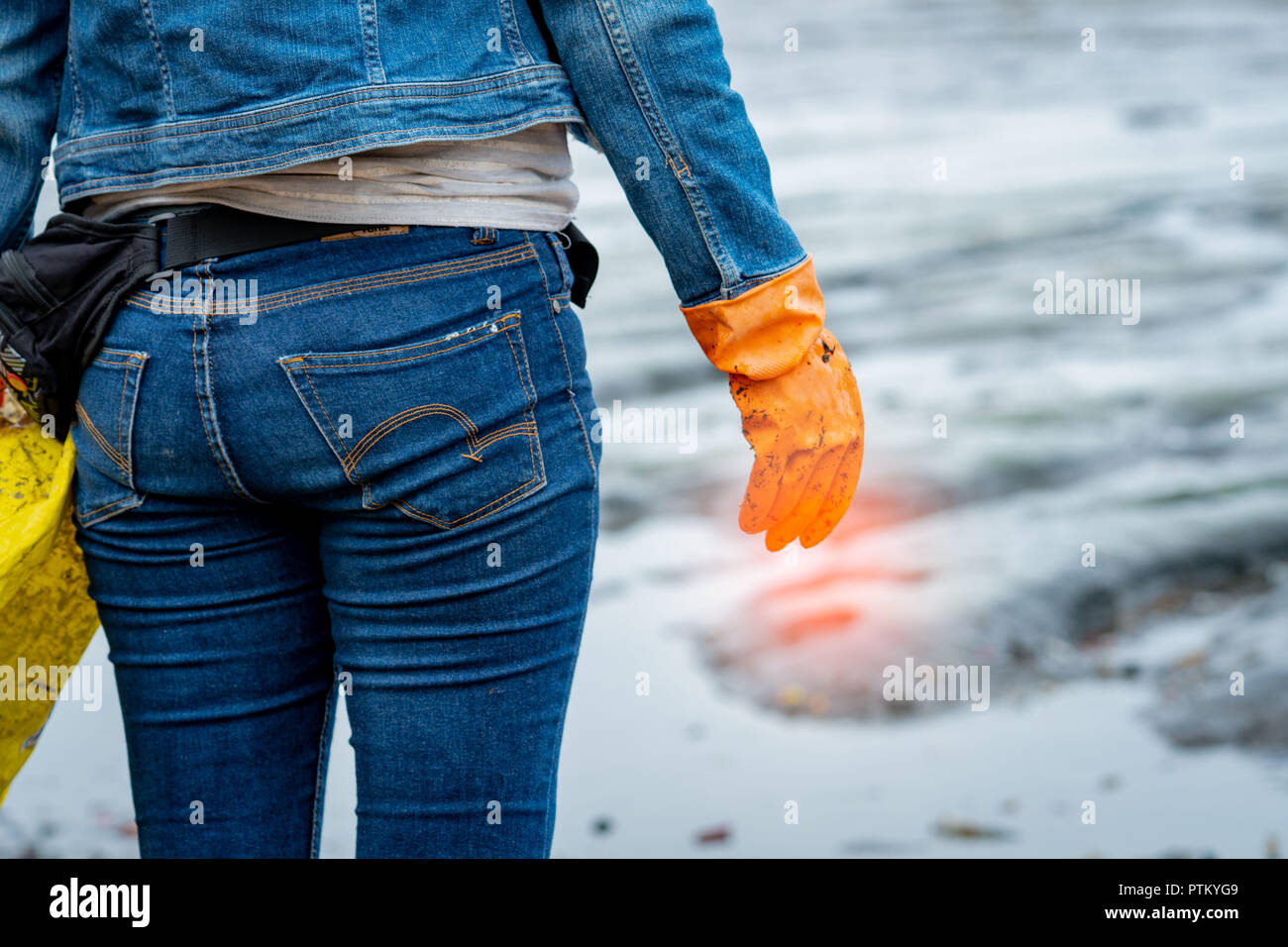 Los voluntarios llevar vaqueros y camisetas de mangas largas y llevar  guantes de goma de color naranja para recoger la basura en la playa. El  entorno de la playa. Limpieza de la
