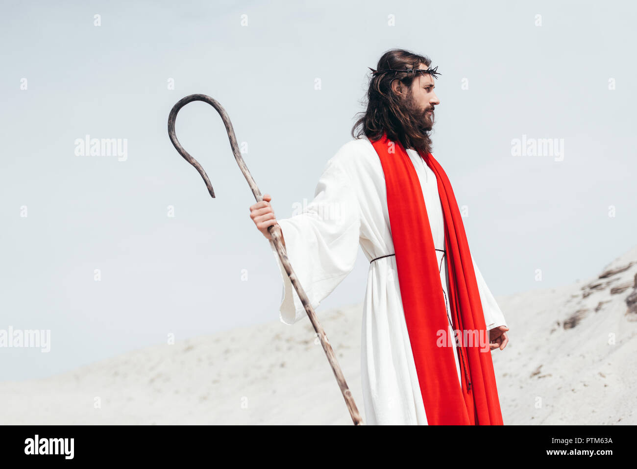 Imagen recortada de Jesús de túnica y fajín rojo en el desierto