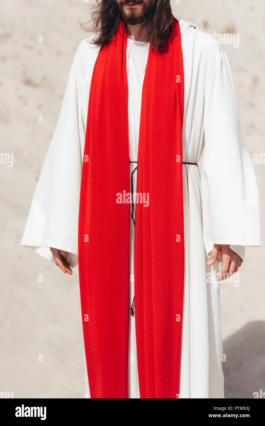 Imagen recortada de Jesús de túnica y fajín rojo en el desierto