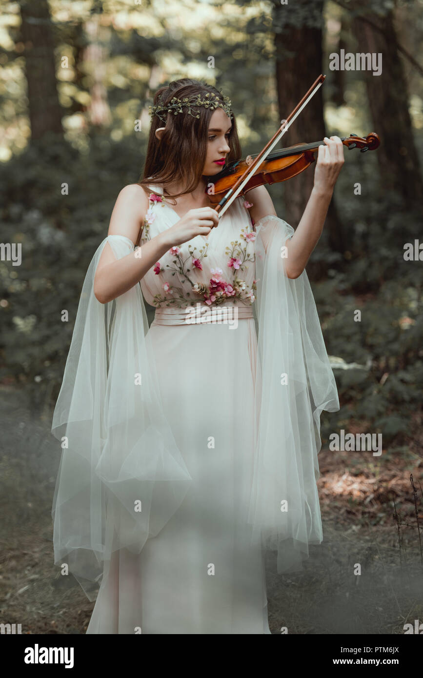 Hermoso elfo místico en elegante vestido de flores en el bosque