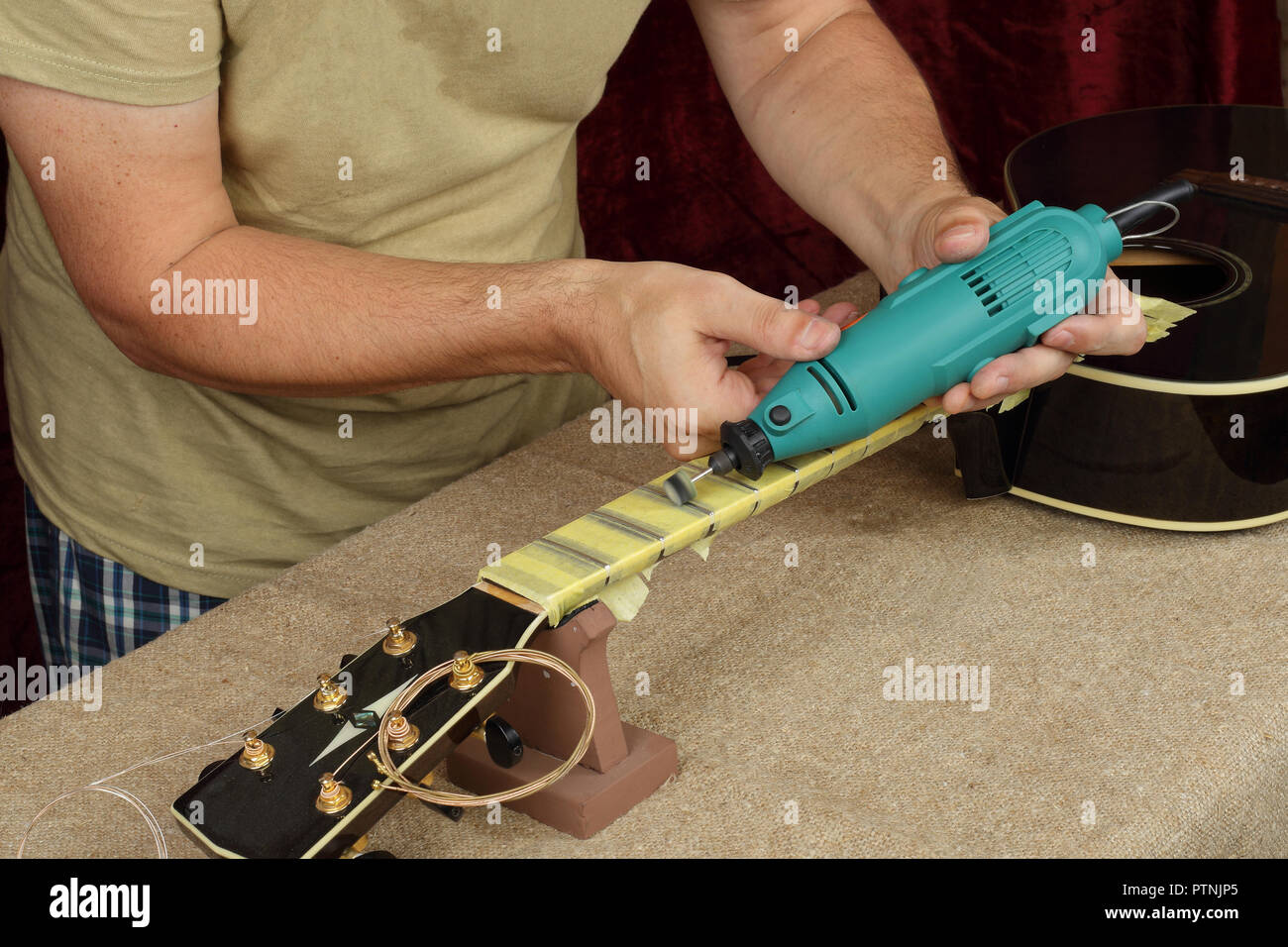 Guitarra instrumentos musicales - Trabajador de reparación y servicio de  pulido en el cuello de la guitarra frets dremel y pegar GOI Fotografía de  stock - Alamy