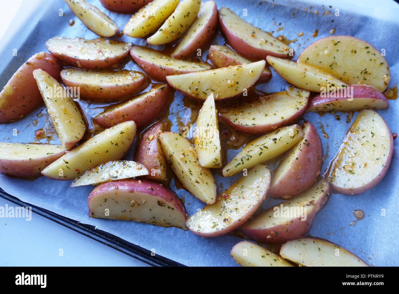 Rodajas de patata cruda sobre la bandeja para hornear. Foto de stock