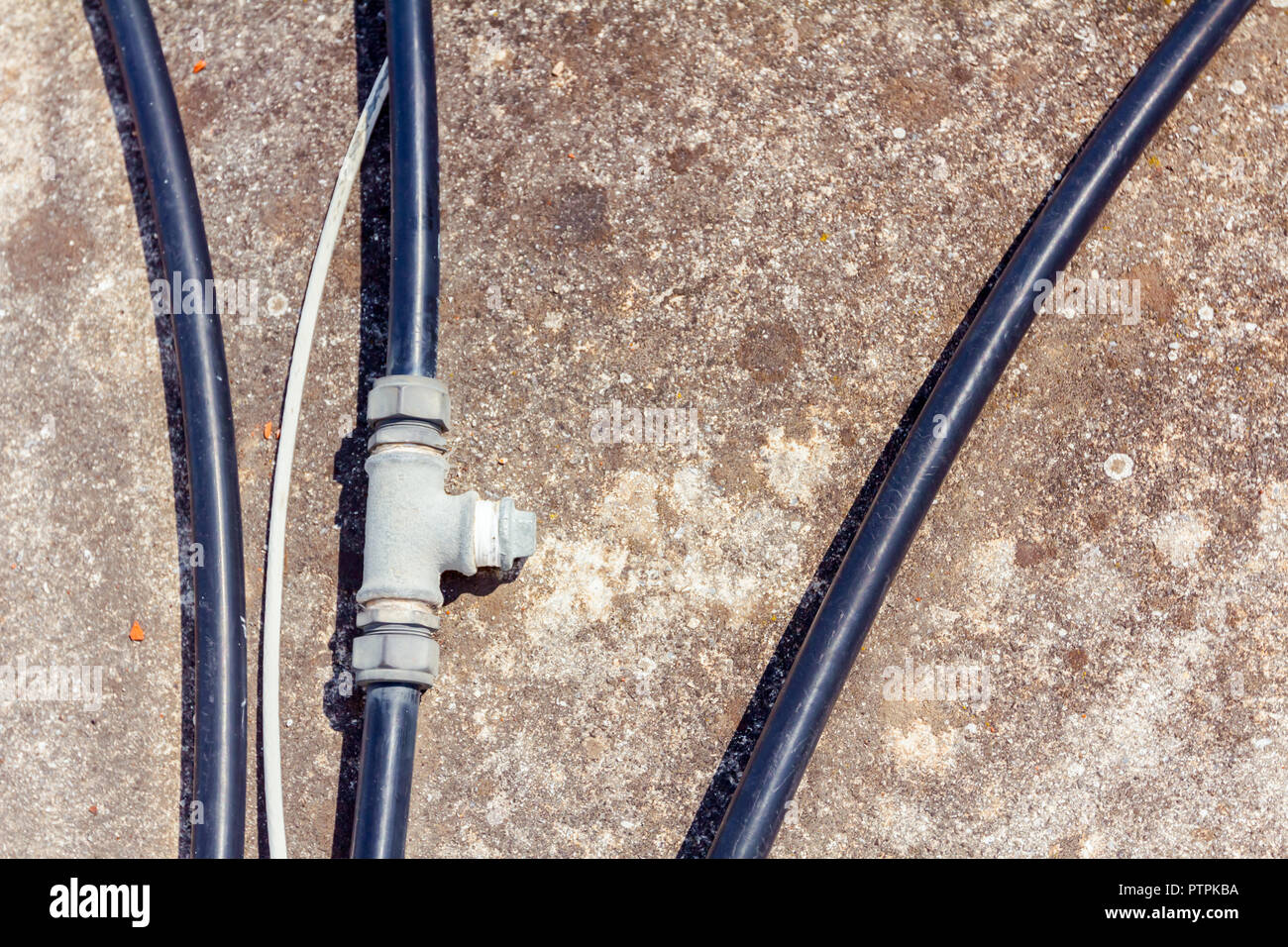Algunas mangueras de agua de plástico negro con bifurcación parte se  colocan sobre el suelo de cemento Fotografía de stock - Alamy