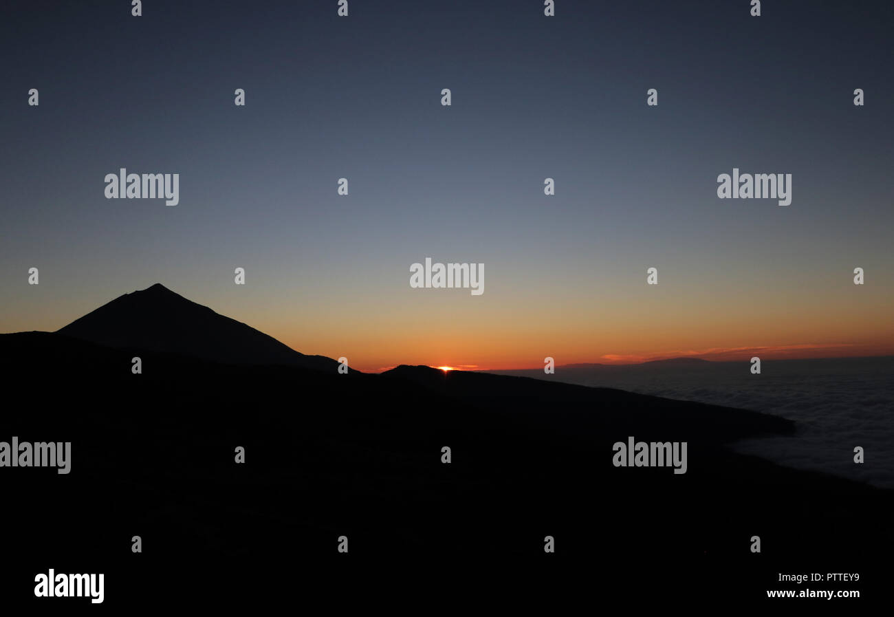 Vista del volcán Pico del Teide (l) en la isla canaria de Tenerife durante la puesta de sol sobre las nubes y a través de la Monta-a Blanca (white mountain"), que 18.09.2018 sólo ligeramente fuera de la cubierta de nubes cerradas (r) sobresalga. Su cumbre plana sobre el flanco oriental del Pico del Teide domina con 2748 m de altura en el borde de las montañas de Ca Cañada su caldera. Dawith es la Monta-a Blanca después del Pico del Teide (3718 m) y el Pico Viejo (3135 m) el tercer pico más alto de Tenerife. El Pico del Teide (también Teyde) es la montaña más alta de España. Pertenece al municipio de La Orotava. En 2007 Foto de stock