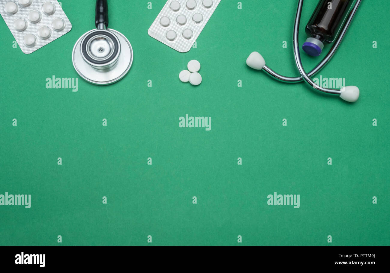 Estetoscopio y tabletas de pastillas aislado sobre un fondo verde, imagen conceptual Foto de stock