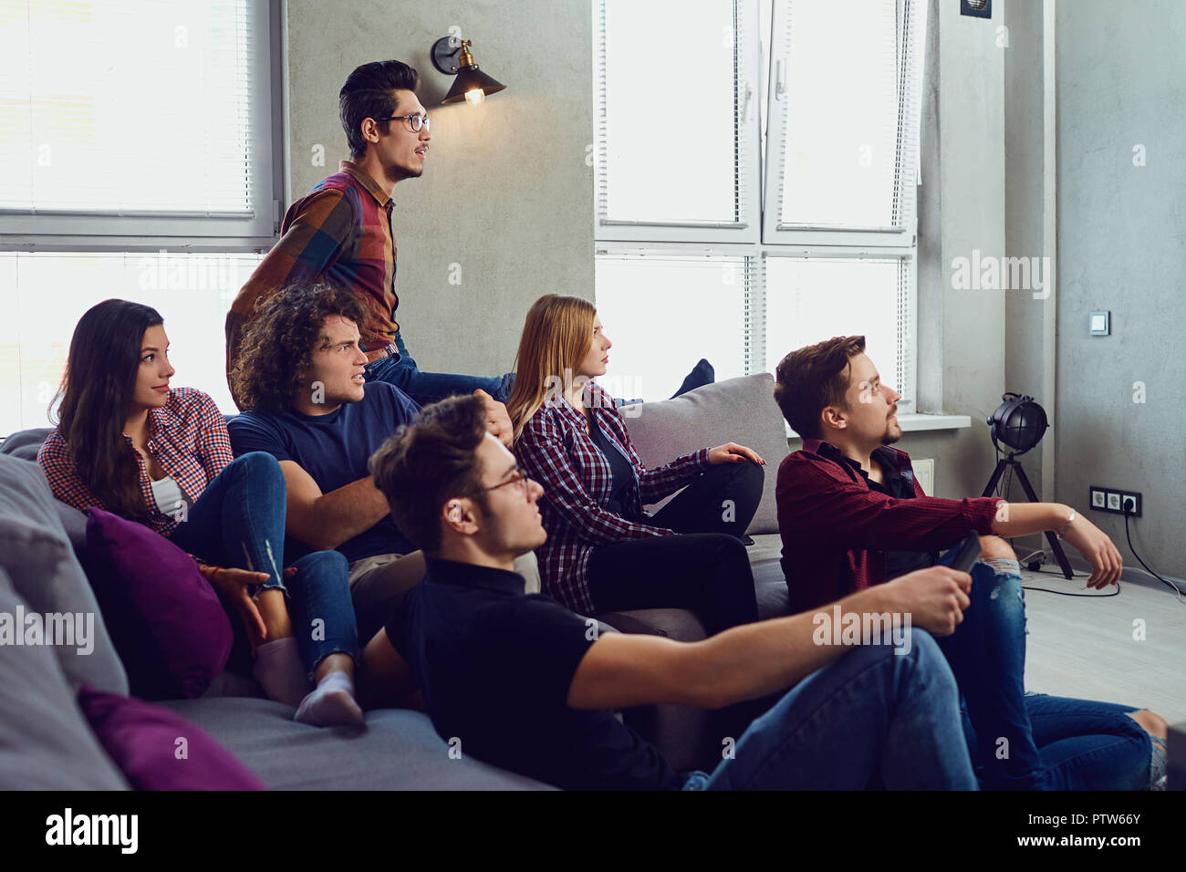 Un grupo de amigos se divierten viendo la televisión en la habitación. Foto de stock