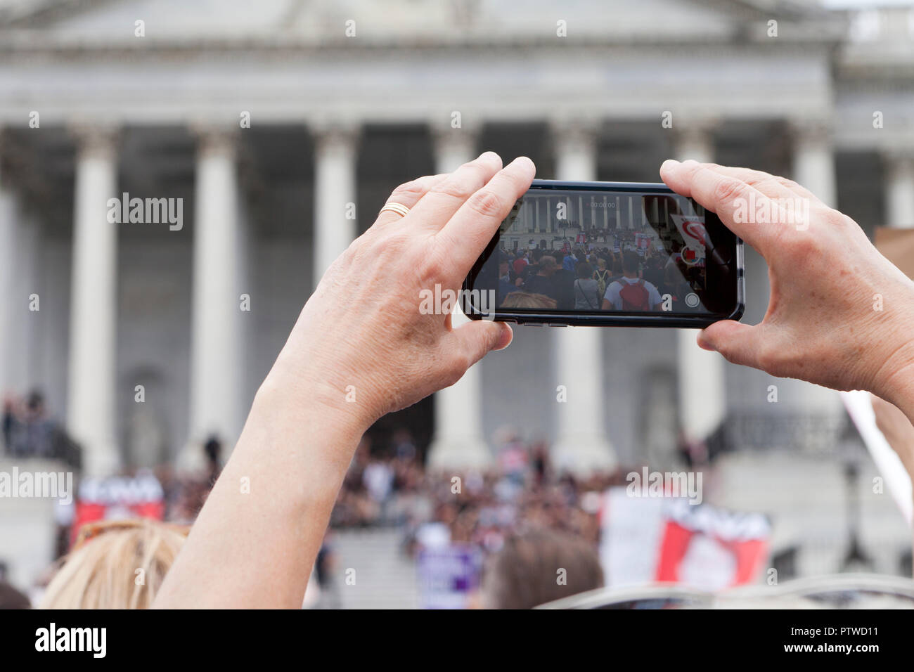 Mujer graba vídeo de protesta política mediante un teléfono móvil (iPhone) - EE.UU. Foto de stock