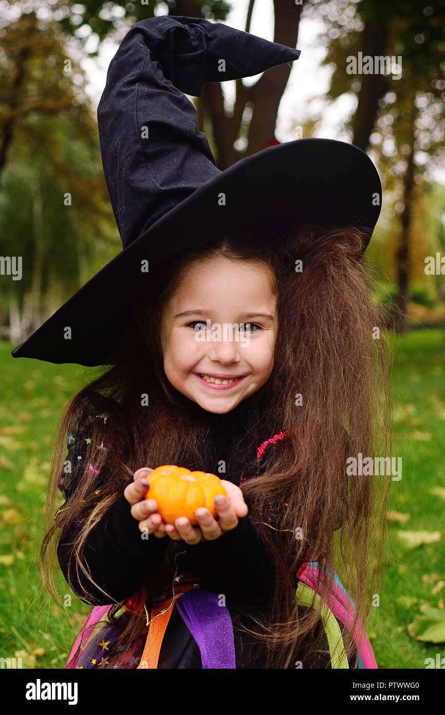 Lindo bebé niña en disfraz de carnaval y en el sombrero de la bruja con  poco en manos sobre halloween calabaza sonriendo a la cámara Fotografía de  stock - Alamy