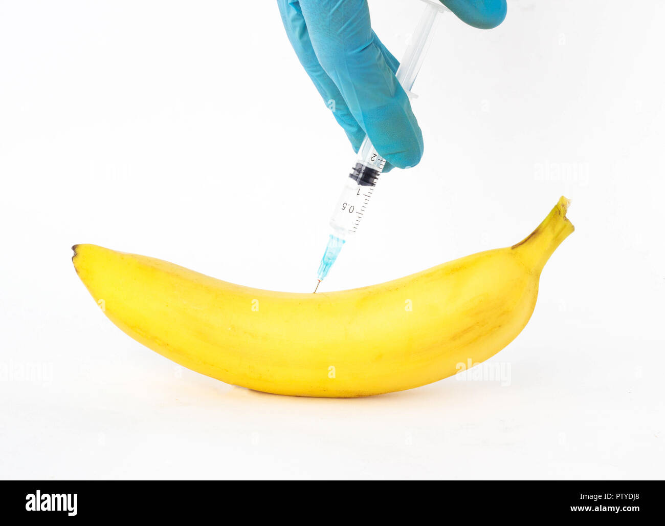 Plátano sobre un fondo blanco en el que se inyecta OMG y nitratos, close-up, organismos modificados genéticamente, los nitratos Foto de stock
