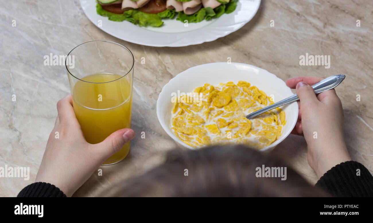 Una chica come cereales con leche delante de la escuela Foto de stock