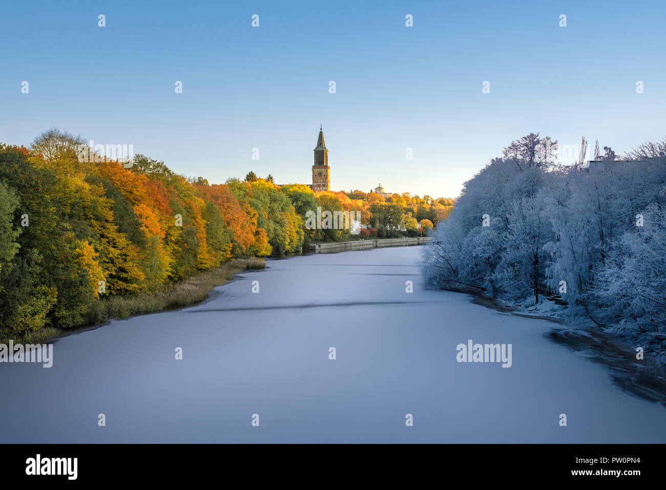 Imagen de transición desde el otoño hasta el invierno en una sola imagen con Frozen River y colorido follaje de otoño y la catedral de Turku en segundo plano. Foto de stock