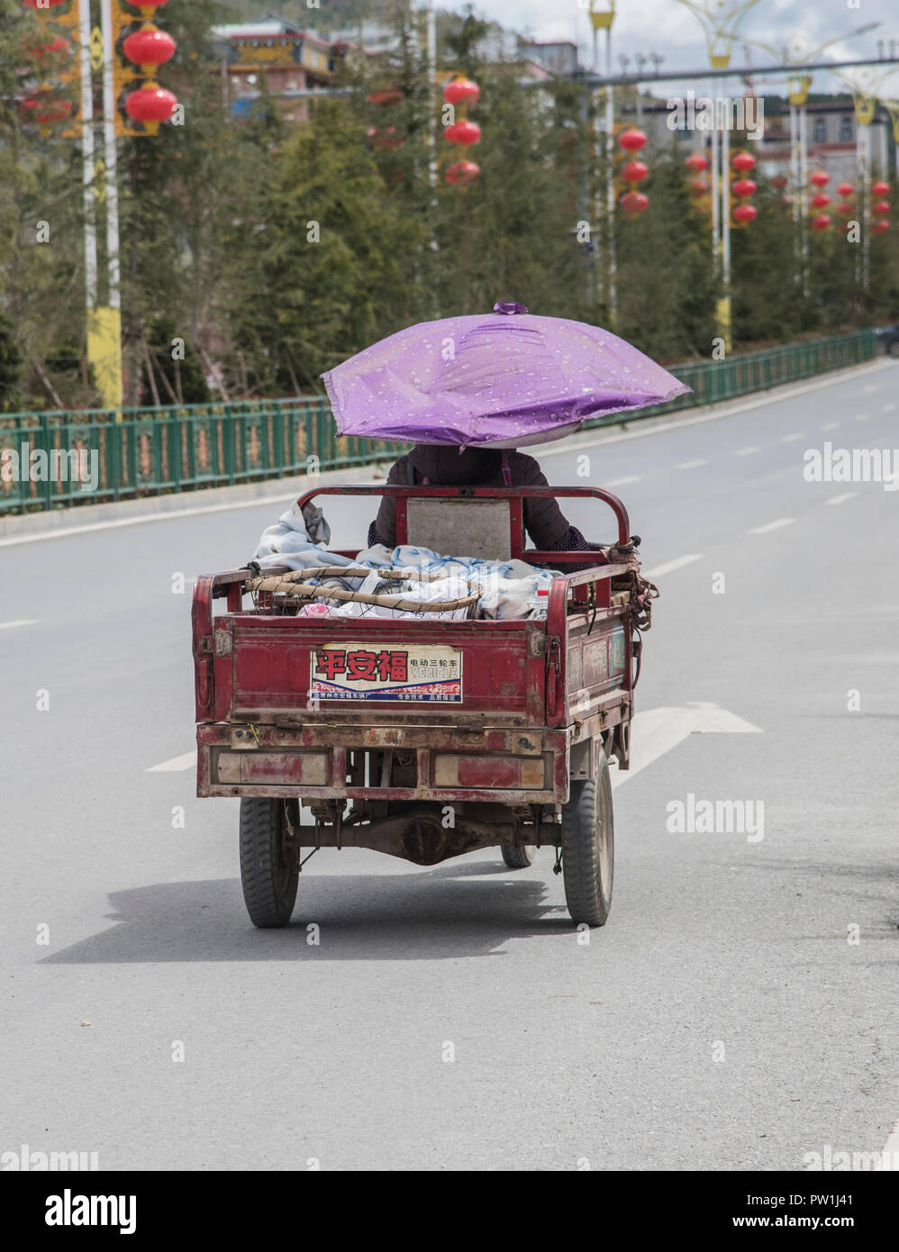 Persona China que monta un viejo motor a lo largo de una carretera principal en la provincia de Yunnan del suroeste de China Foto de stock