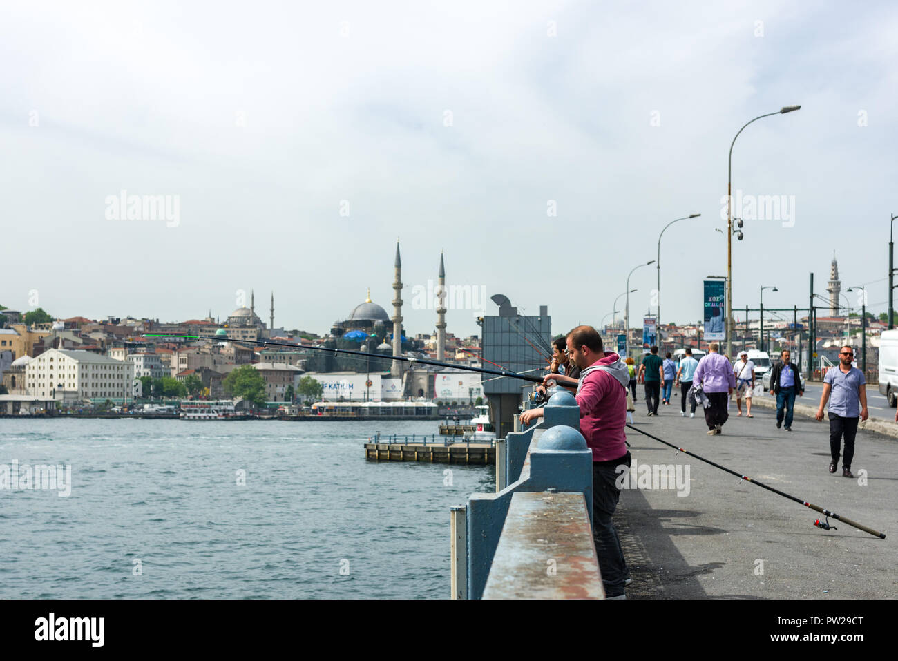 Un grupo de pescadores de pie en el puente de Galata con sus cañas de pescar sobre el lado, Estambul, Turquía Foto de stock