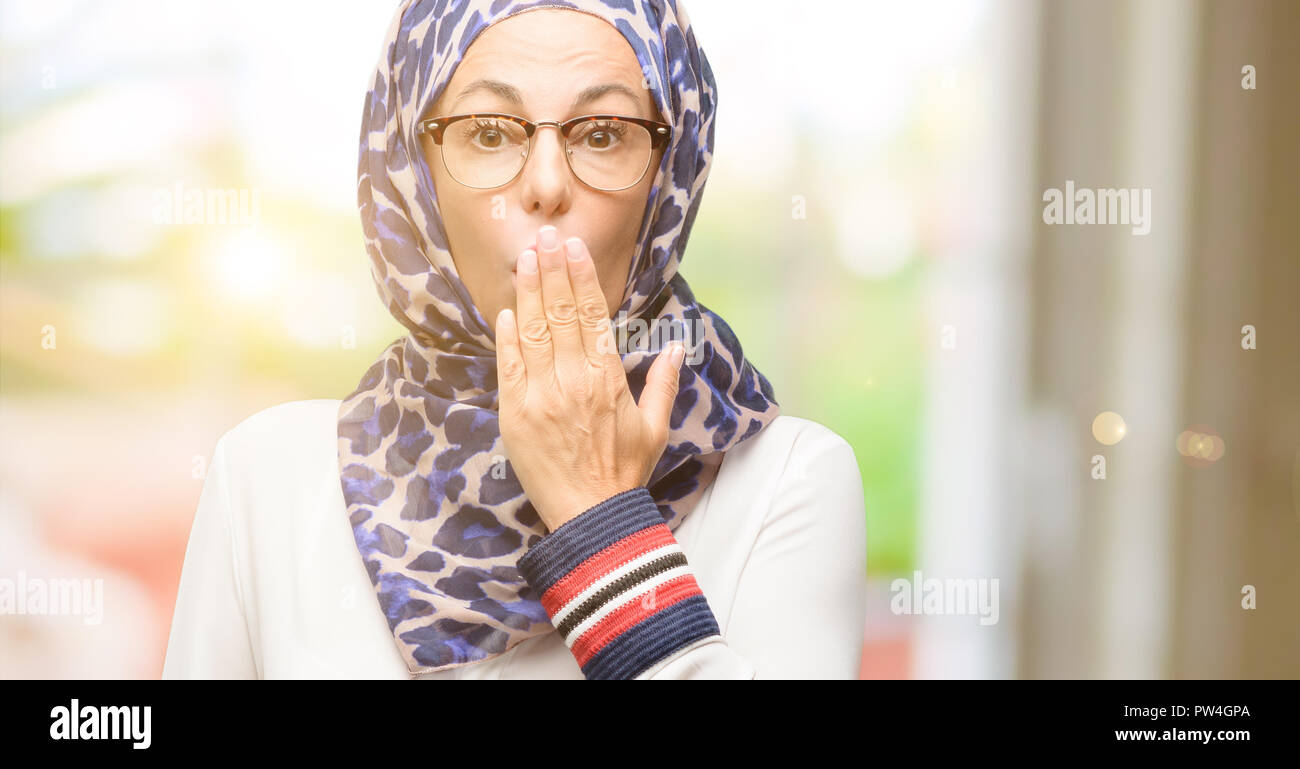 Edad media los árabes musulmanes mujer vistiendo el hijab cubre boca en estado de shock, parece tímido, expresando el silencio y confundir los conceptos, asustada Foto de stock