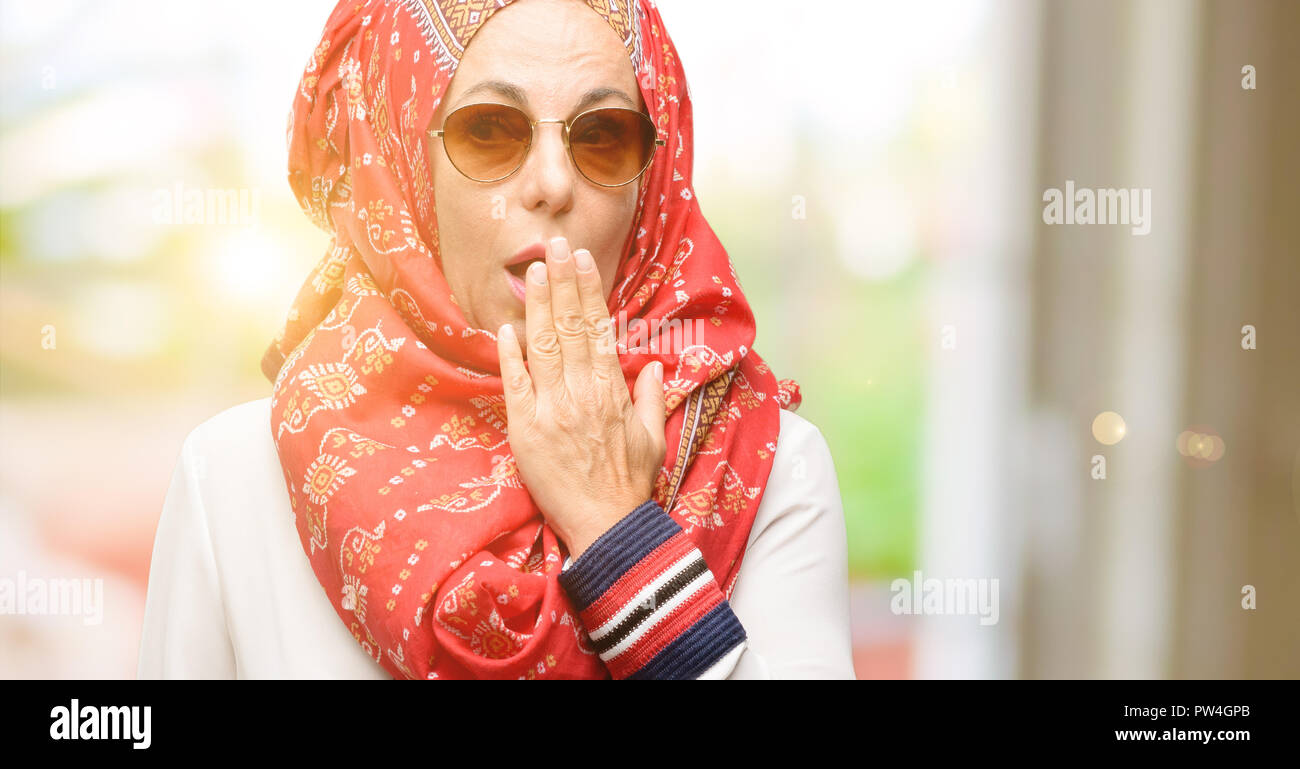 Edad media los árabes musulmanes mujer vistiendo el hijab cubre boca en estado de shock, parece tímido, expresando el silencio y confundir los conceptos, asustada Foto de stock