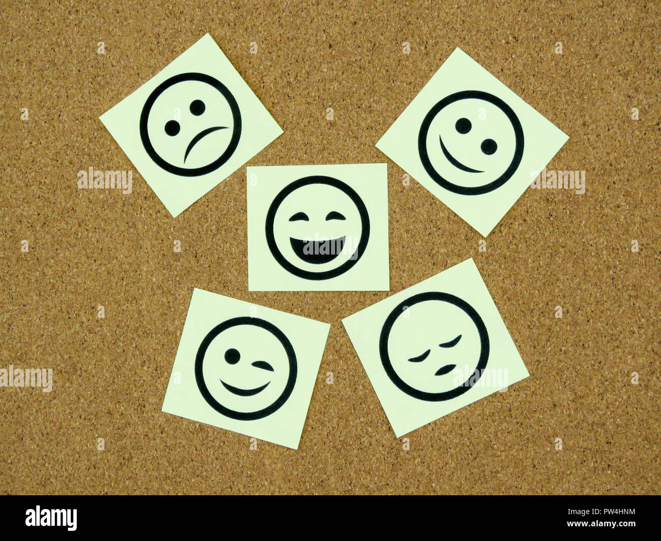Unas cuantas notas adhesivas amarillas con caras sonrientes sobre ellos en  un fondo de tablero de corcho Fotografía de stock - Alamy