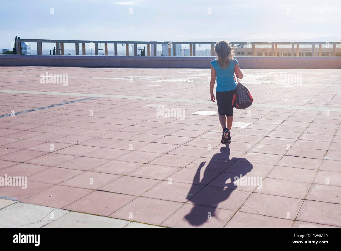 Vista trasera de la atleta femenina con mochila caminando por sendero contra el cielo durante el día soleado Foto de stock