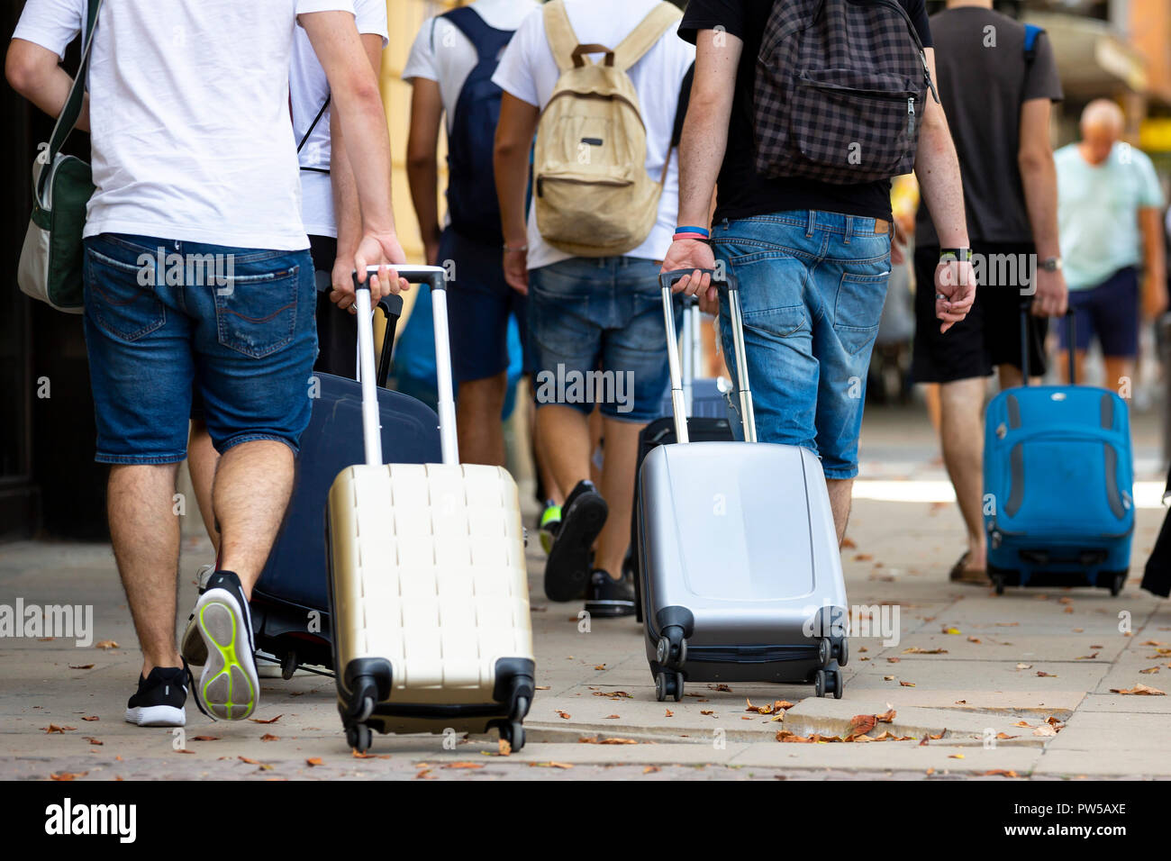 Las personas con maletas con ruedas son vistos desde sus espaldas en la  calle caminando. La gente irreconocible Fotografía de stock - Alamy