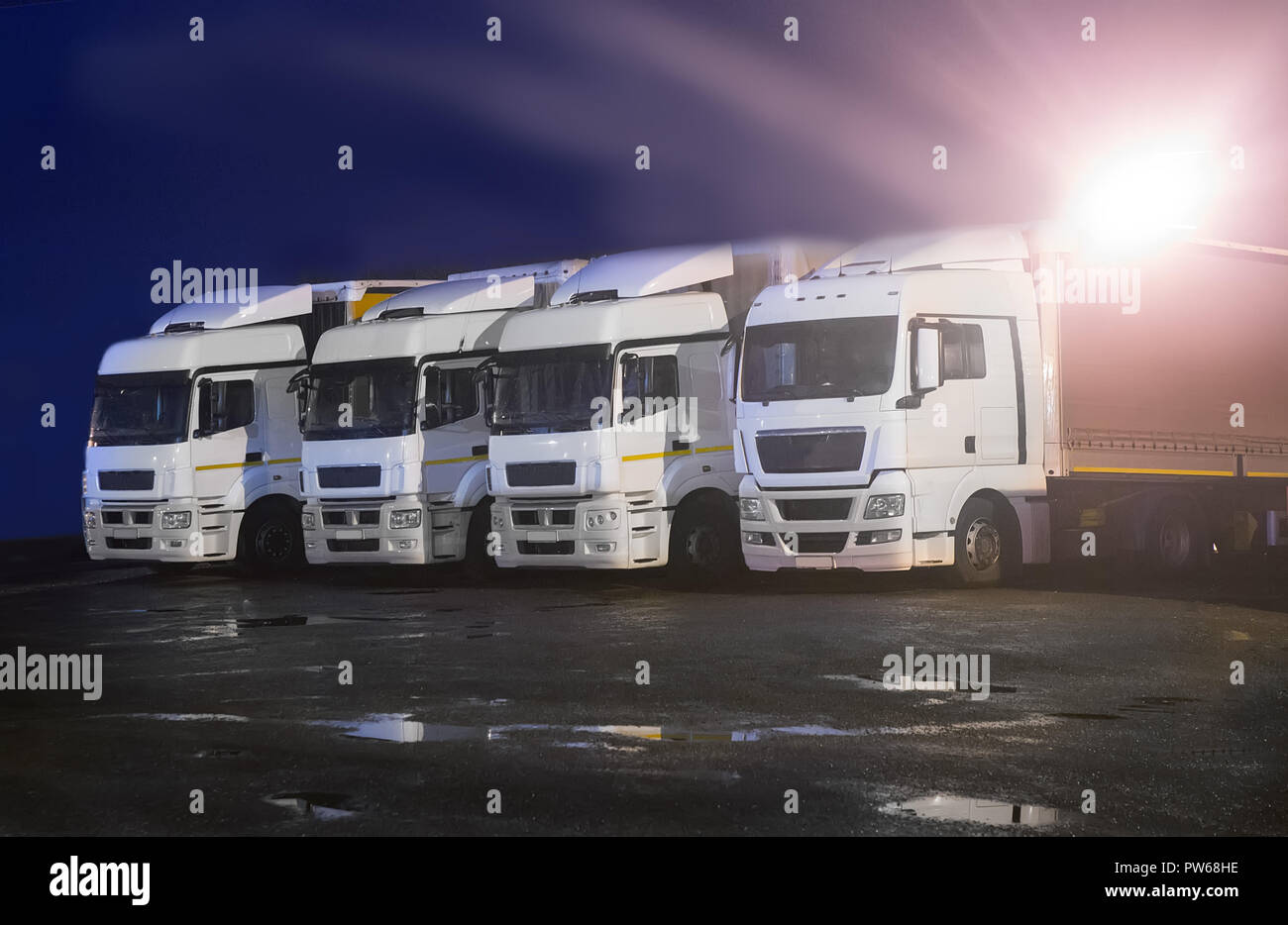 Grandes camiones por la noche en el aparcamiento bajo linterna Foto de stock
