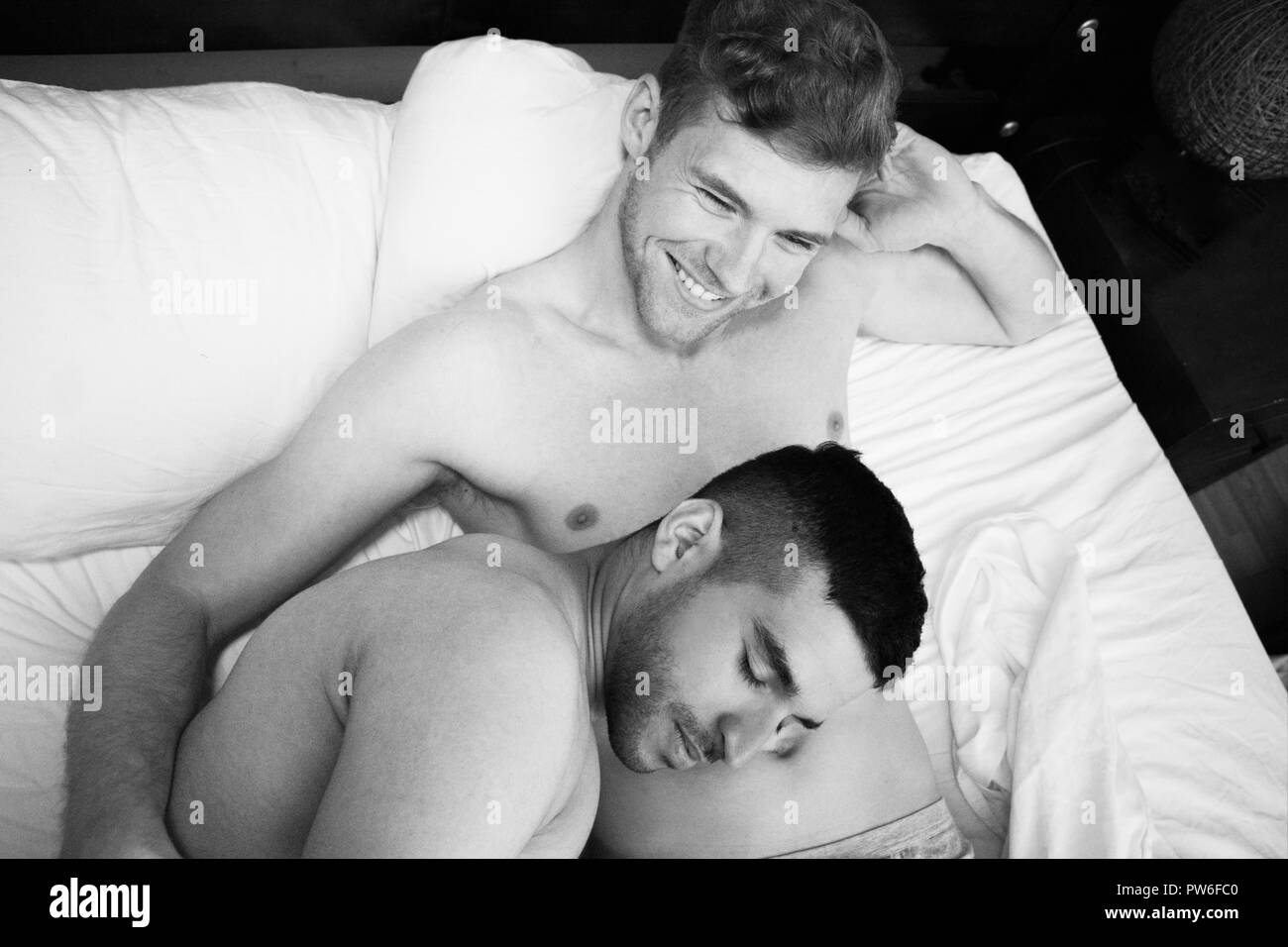 Guapo desnudo pareja gay en la cama con uno durmiendo en el vientre de su  pareja como los demás sonrisas Fotografía de stock - Alamy