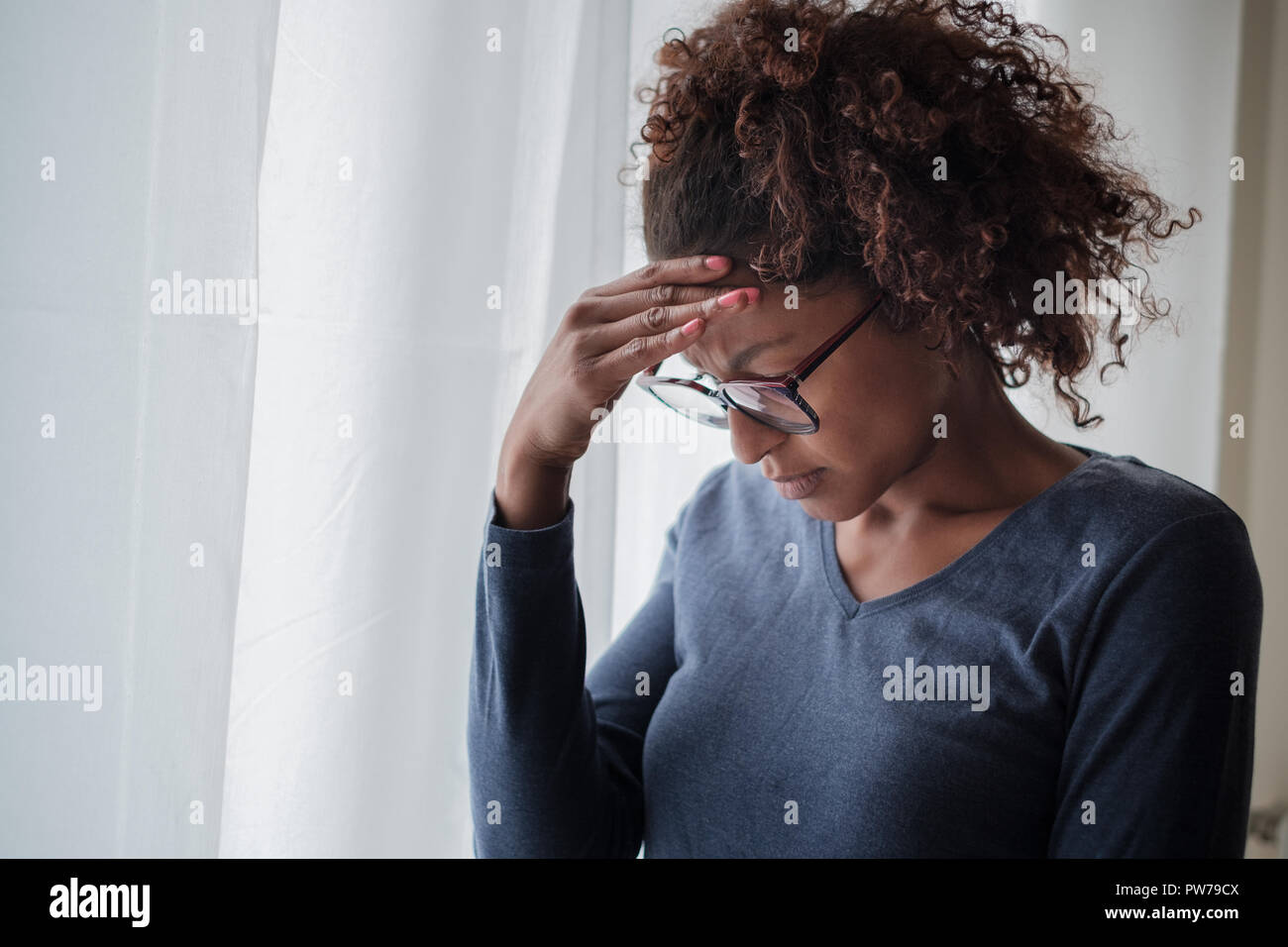 Mujer negra solitaria cerca de la ventana pensando en algo Foto de stock