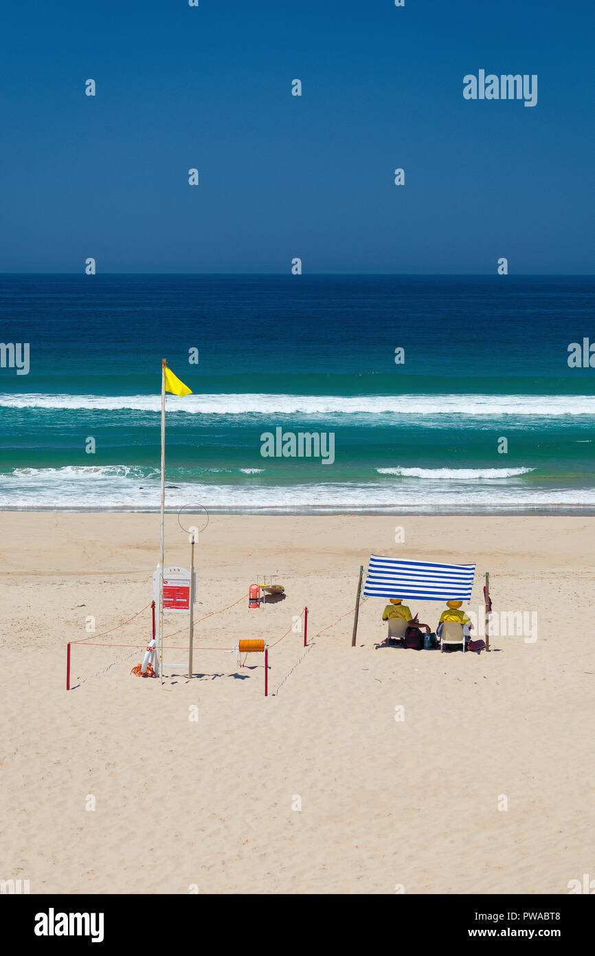 Dos socorristas sentados bajo el parasol de playa en Alentejo, Portugal Foto de stock